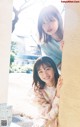 A couple of young women leaning against a wall.