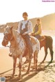 A couple of people riding on the backs of horses on a beach.