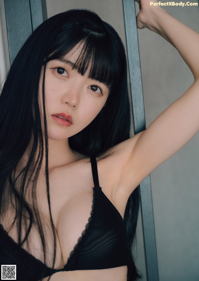 A woman with long black hair wearing a black bra.