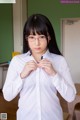 A woman in a white shirt and glasses adjusting her tie.