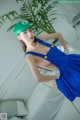 A woman in a blue dress and a green hat posing for a picture.