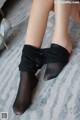 A woman wearing black stockings and high heels on a bed.