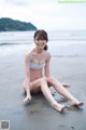 A woman in a bikini sitting on the beach.