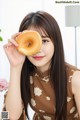 A woman holding a donut in front of her face.