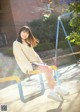 A woman sitting on a swing in a park.